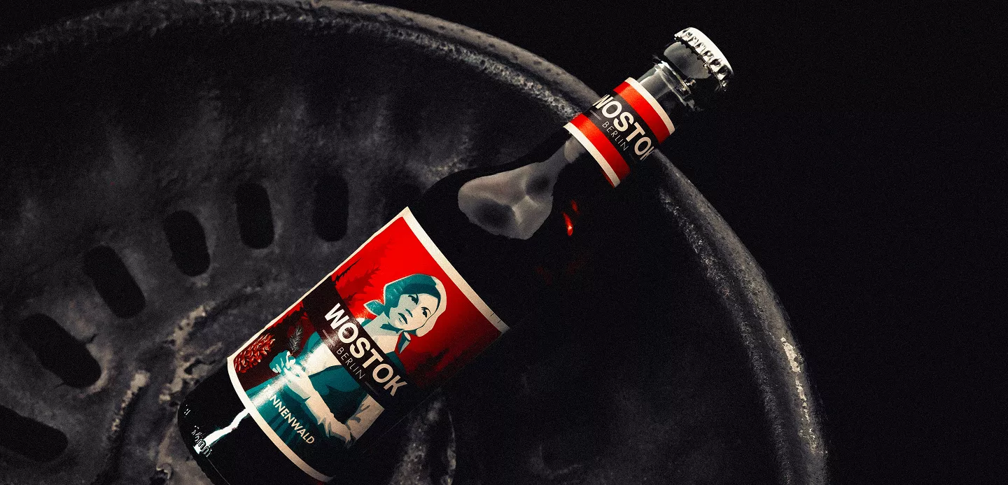 A dramatic product shot of what appears to be a "MOSTOK" branded bottle with bold red and white labeling against a dark, textured background